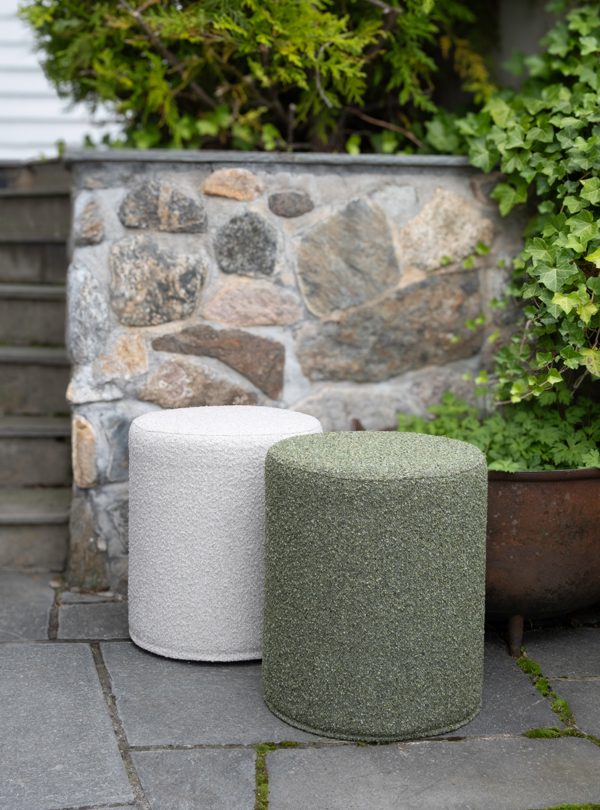 Two Mingle poufs for outdoor use, one in cream and the other in green, placed on a stone patio.
