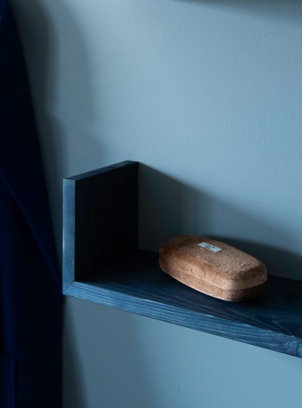 Close up of a blue Gren wall shelf pine against a light blue wall
