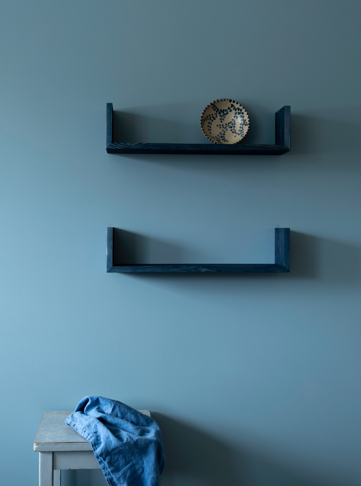 Blue painted Gren wall shelves pine against a light blue painted wall.
