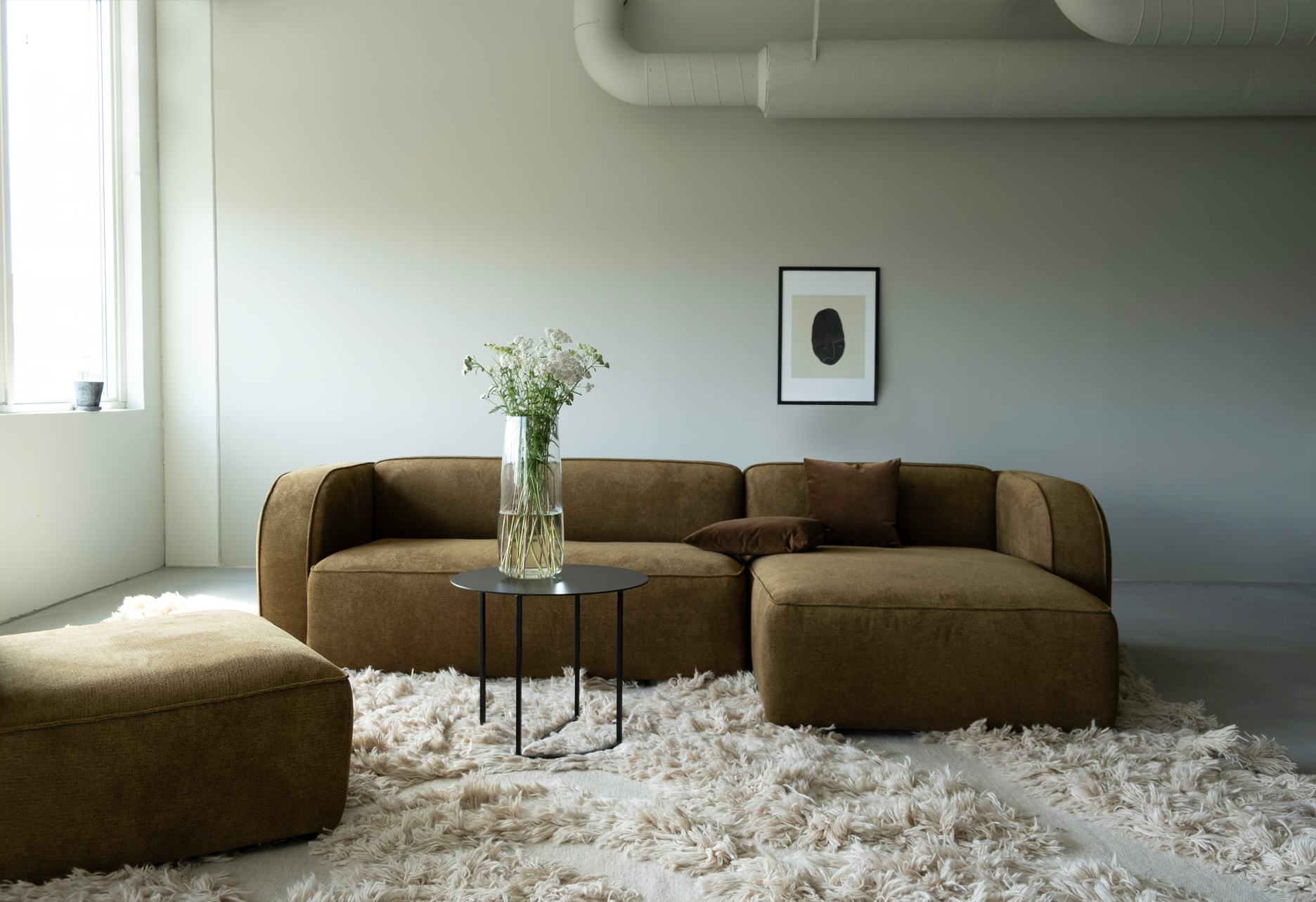 Sva module sofa in brown, arranged on a shaggy cream rug in a minimalist living room.